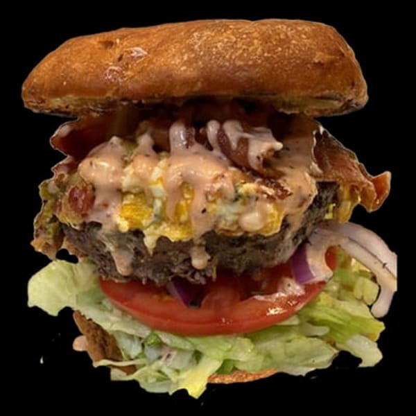 A Main Event Grill burger with bacon, egg, sauce, red onion, tomato, and lettuce.