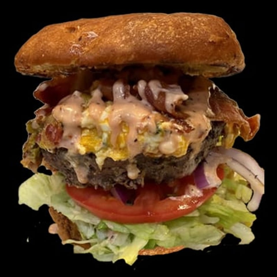 A Main Event Grill burger with bacon, egg, sauce, red onion, tomato, and lettuce.